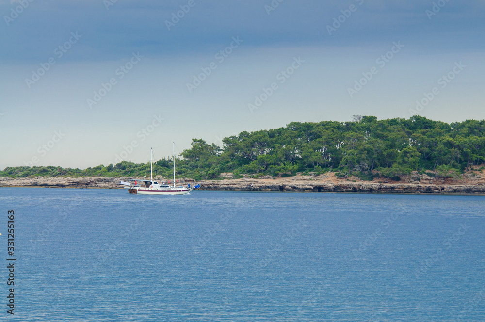 Pleasure yacht against a stone coast Pleasure yacht against a stone coast