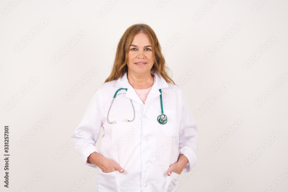 Confidence and business concept. Portrait of charming successful young doctor woman, smiling broadly with self-assured expression while holding hands in pockets. Confidence and business concept. Portrait of charming successful young doctor woman, smiling broadly with self-assured expression while holding hands in pockets.