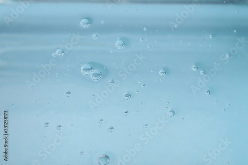 Pure transparent cosmetic gel on light blue background, closeup