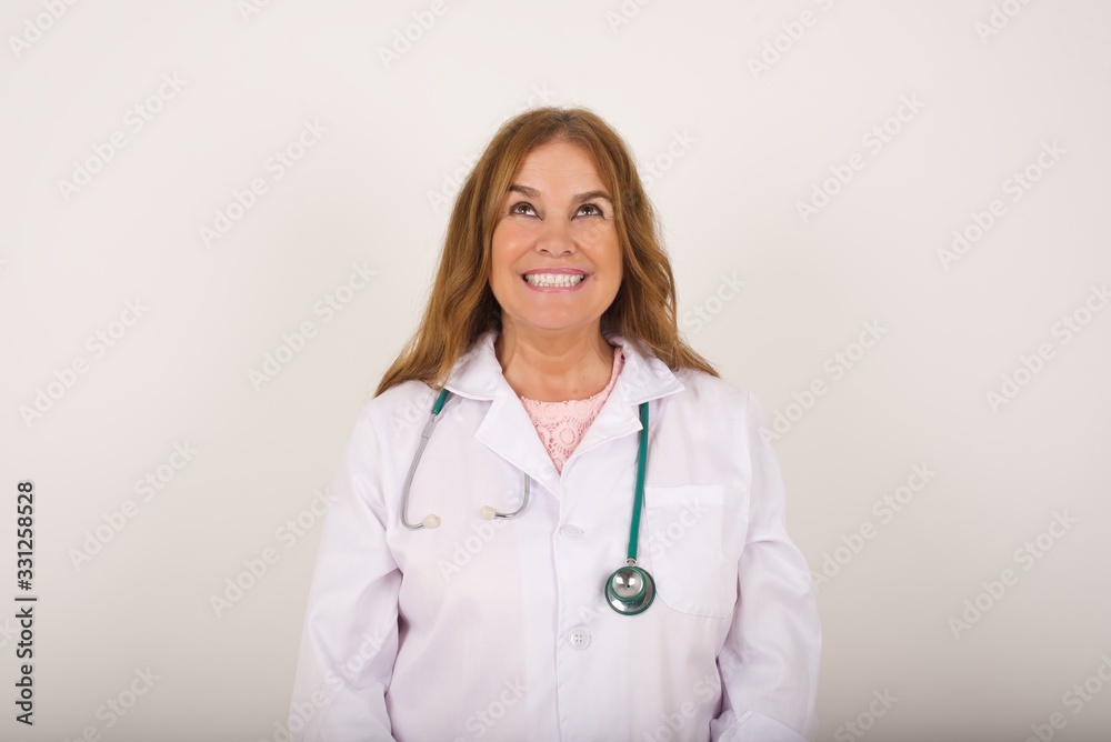 Portrait of charming doctor female wearing medical uniform looking up with enigmatic smile. Portrait of charming doctor female wearing medical uniform looking up with enigmatic smile.