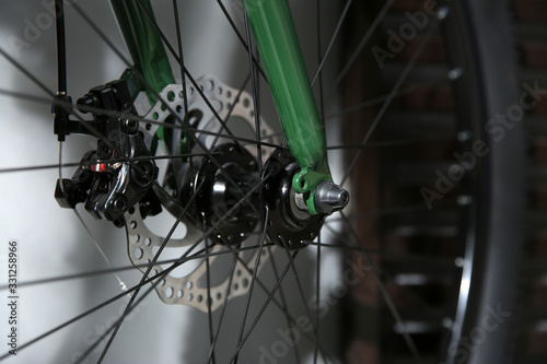 Modern green bicycle near grey wall indoors, closeup