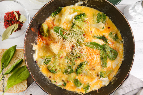 scrambled eggs, with spinach and broccoli and cheese in a pan close- up