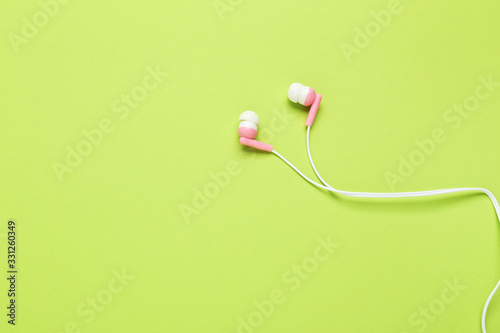 Pink earphones on green background