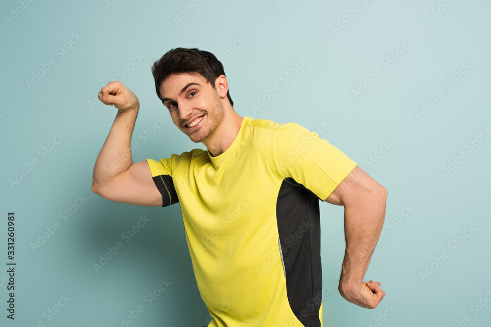 muscular smiling sportsman gesturing in yellow t-shirt on blue muscular smiling sportsman gesturing in yellow t-shirt on blue
