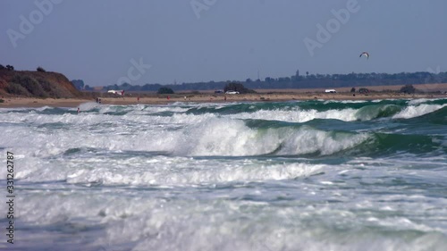 Spectacular big waves hit beach during storm. Kite surfers ride high waves.