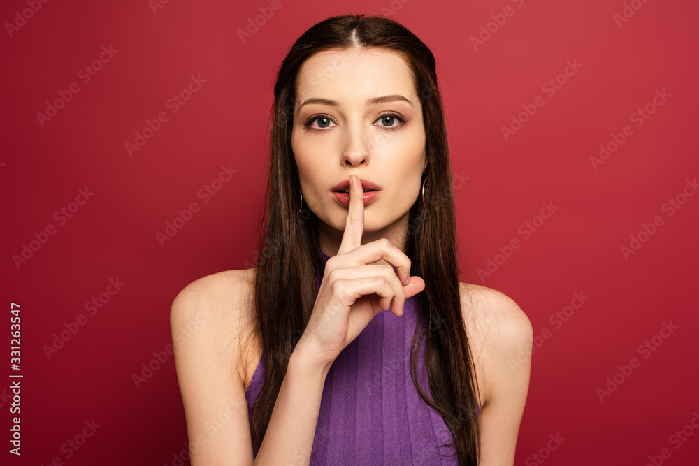 Fototapeta premium portrait of beautiful woman showing silence symbol on red