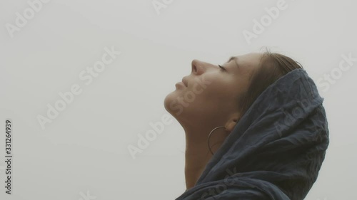 Side view of natural female face looking above close up on white sky background. Macro shot of young woman enjoying freshness of air slow motion copy text space. Facial cosmetics skincare products