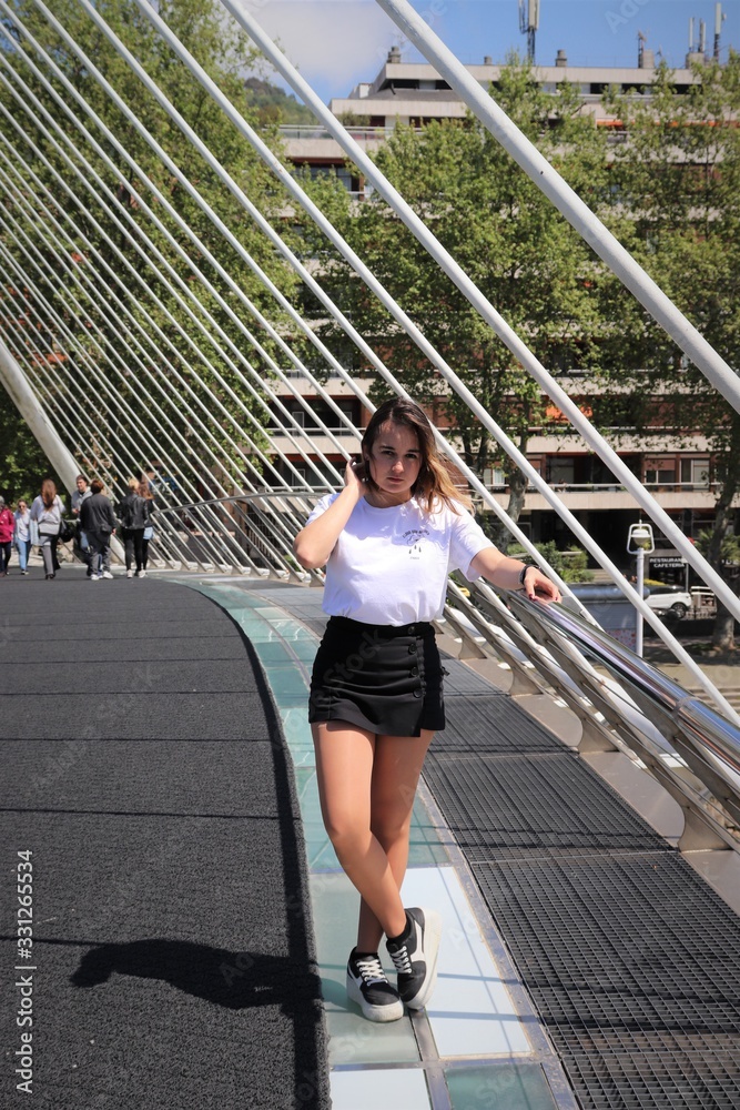 mujer en un puente con camiseta blanca y falda negra
