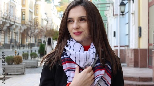 Portrait of a smiling European woman in a striped scarf in the city. Stock footage. Slow motion