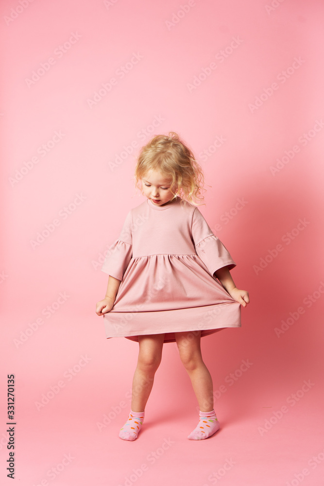 A little girl in a pink dress is spinning and demonstrating her outfit. A little girl in a pink dress is spinning and demonstrating her outfit.
