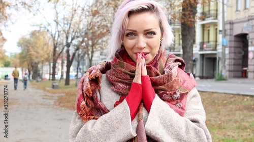 Young woman smiles and warms her hands in the cold.Smiling girl looking at camera.