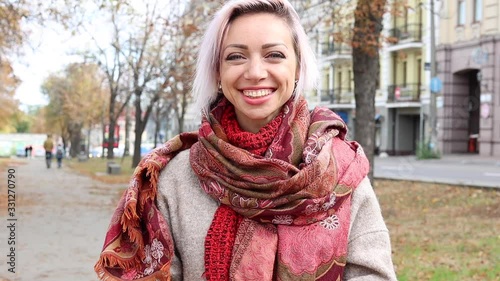 Young woman smiles and waves her hand to friends. A greeting