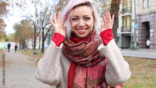Young woman straightens her scarf and smiles while looking at the camera. Lifestyle and positive