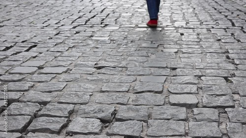 legs of a woman in red shoes come along the road. Concept of walking and reaching goals.