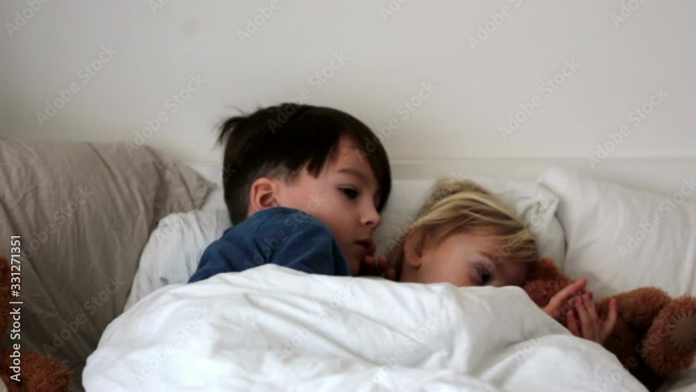 Sick children, toddler and older boy, brothers, lying in bed with a fever, resting Sick children, toddler and older boy, brothers, lying in bed with a fever, resting