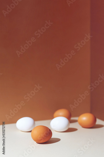 Five brown and white eggs with a hard shadow. They're in the corner of the box.