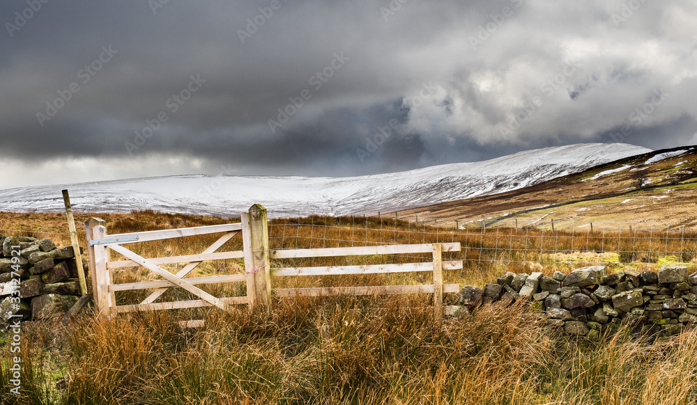 Little Whernside mountain in snow from a wooden fence. Scar House. Nidderdale