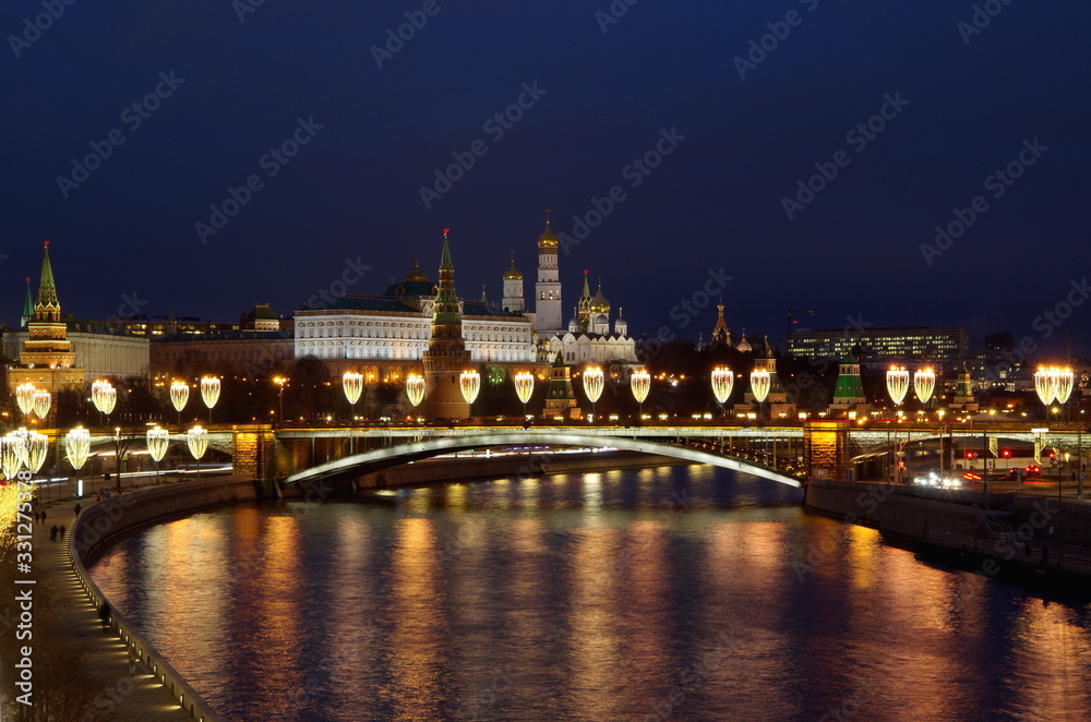 Night view of the Moscow Kremlin, the Big Stone bridge with festive illumination and the Prechistenskaya embankment. Moscow, Russia