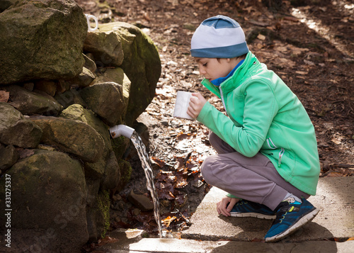 Child drinking water at nature spring