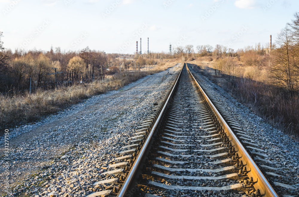 Railroad tracks in the spring. Railroad go towards the factory