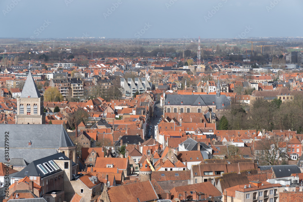 Bruges panorama from the top of the bell tower, red roofs, trees and quiet streets below.