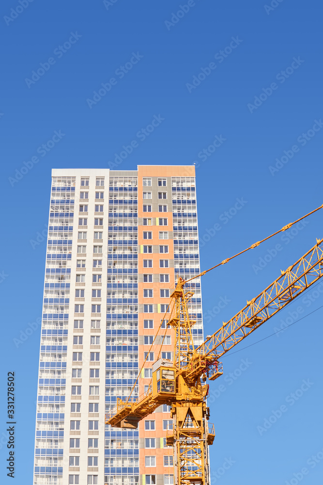 cabin of tower crane and new block of flats on a background of blue sky cabin of tower crane and new block of flats on a background of blue sky