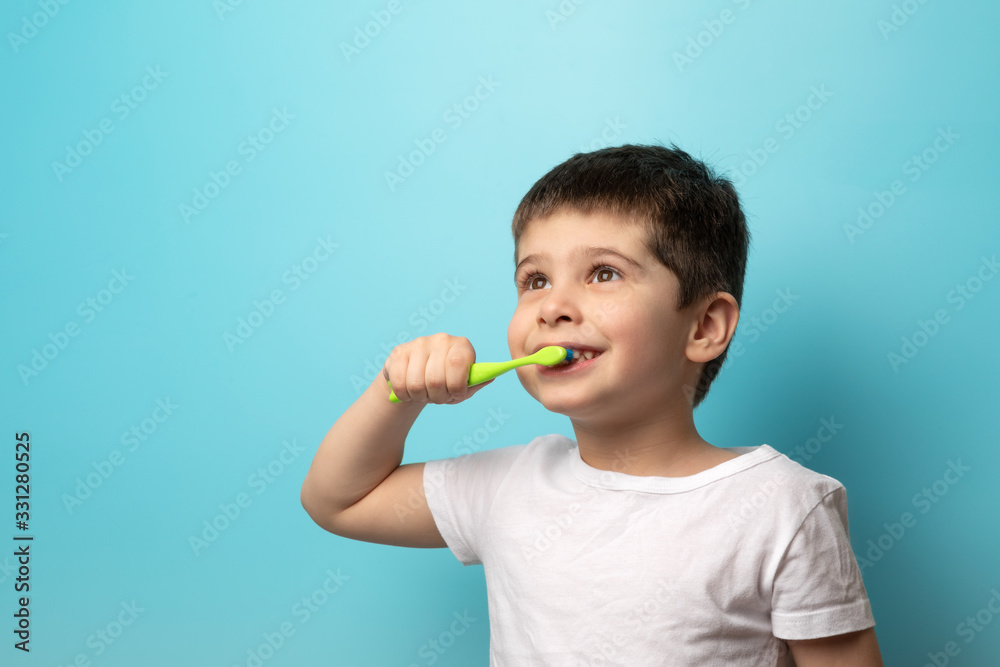 the boy brushes his teeth. A small child with a toothbrush on a blue background the boy brushes his teeth. A small child with a toothbrush on a blue background