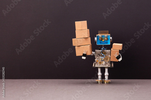 The concept of autonomous robotic delivery of parcels, goods and postal packages. A smiling steampunk robot courier is holding a lot of cardboard boxes with orders. Black wall background copy space