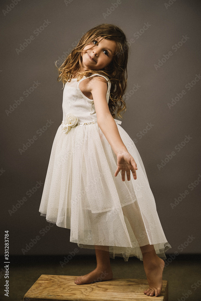 A young girl on gray background doing a dance move