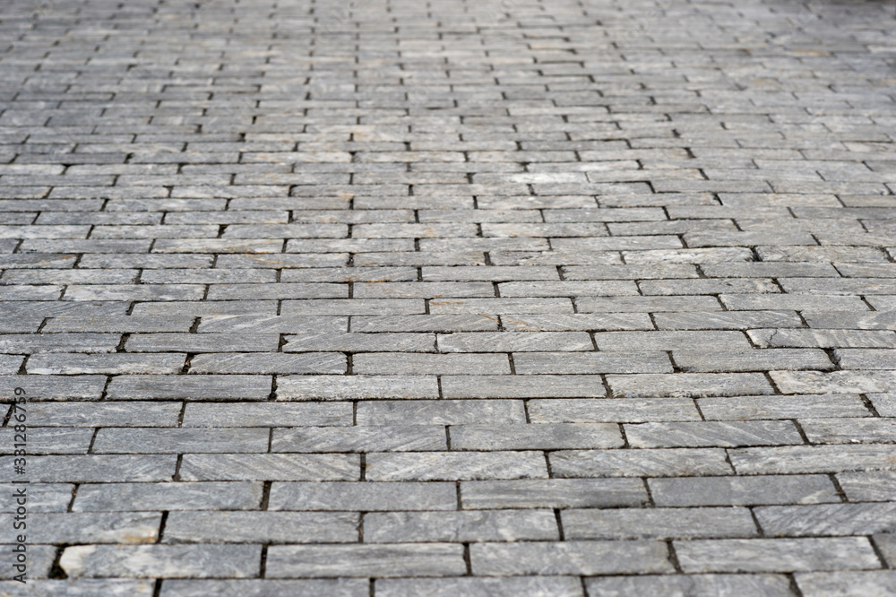 The sidewalk is made of rectangular gray granite bricks . Background