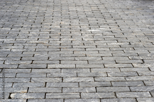 The sidewalk is made of rectangular gray granite bricks . Background