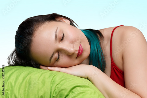 a young girl sleeps with her head on a pillow. With blue background