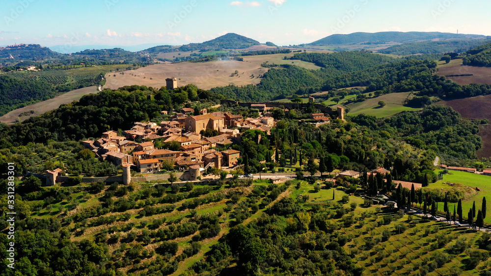 An Italian village with green meadows all over the village. Aerial view with a drone of the beautiful and old village of Monticchiello in Tuscany, Italy