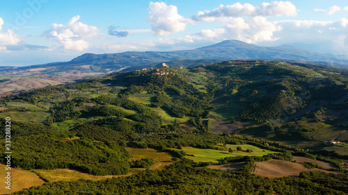 Drone flying over a magnificent authentic Italian village and green meadows. Aerial view of the beautiful old village of rocca d'orcia Tuscany, Italy