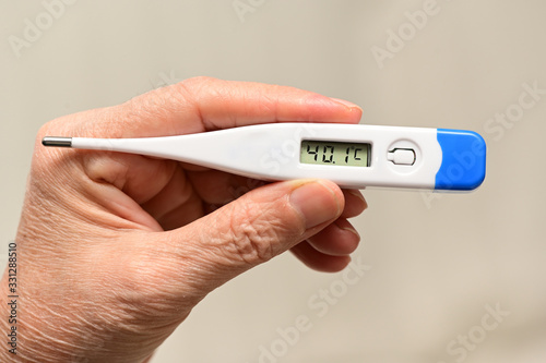 hand holding a thermometer with a high fever temperature of more than 40 celsius