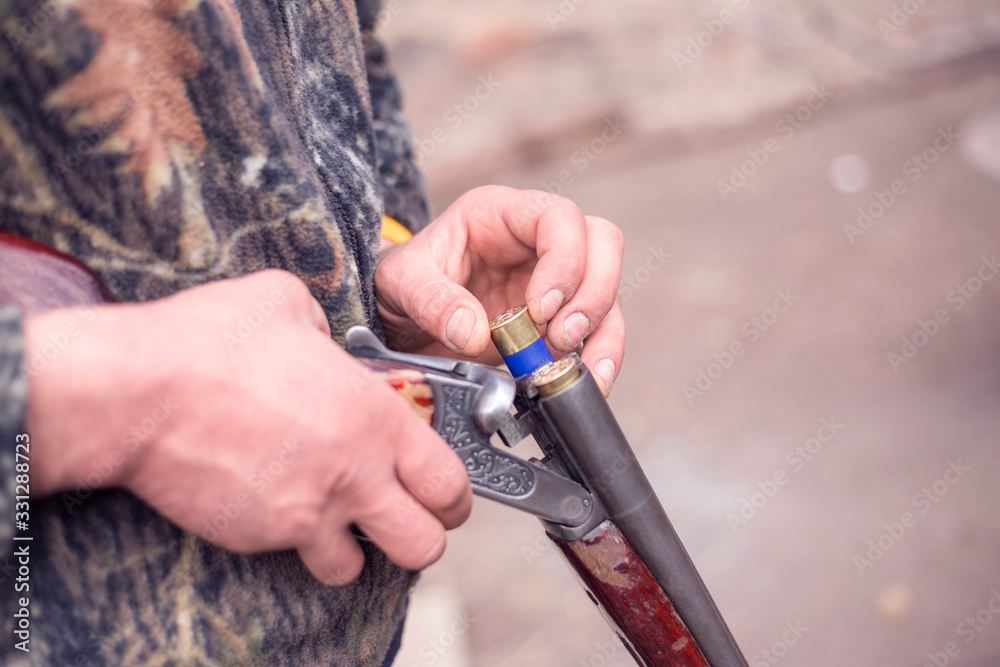 Close up of hunter loading shotgun. Holds a gun and ammunition in his hand