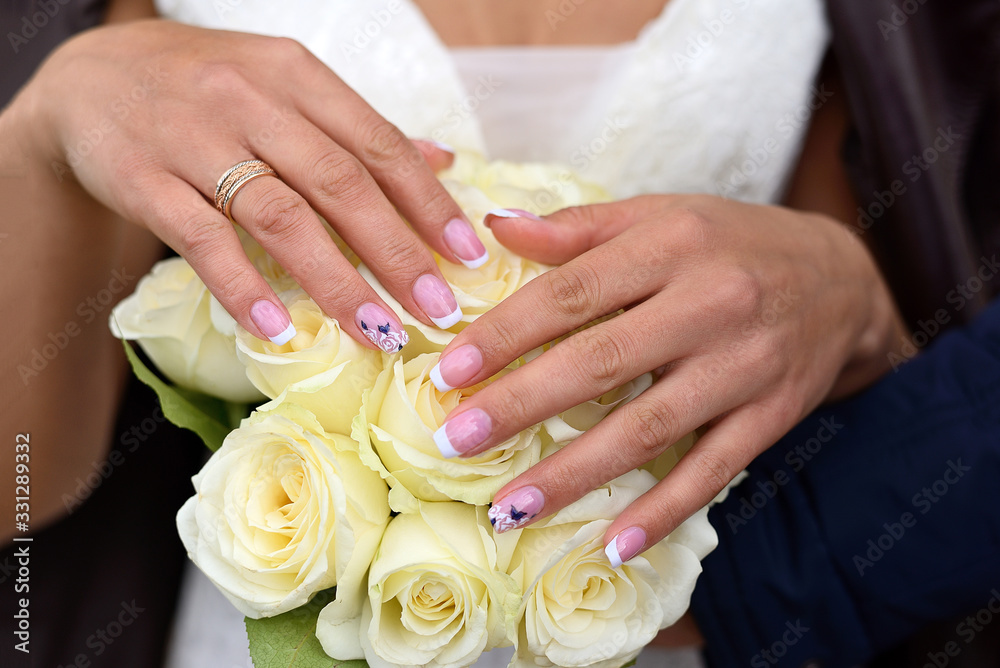 Hands of the bride with ring on a bouquet of white roses Hands of the bride with ring on a bouquet of white roses