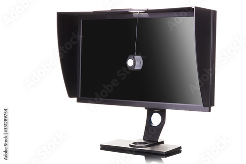 Professional monitor with shading hood and calibrator isolated on white photo