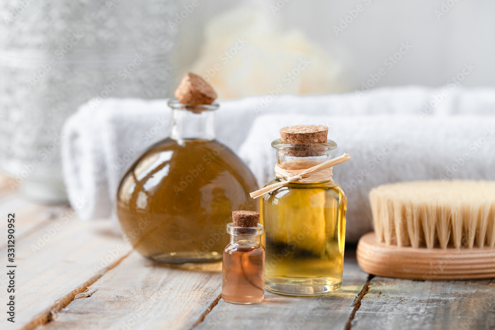 Concept of natural organic oil in cosmetology. Moisturizing skin care and aromatherapy. Gentle body treatment. Atmosphere of harmony relax. Wooden background, white towel, brush. Copy space for text Concept of natural organic oil in cosmetology. Moisturizing skin care and aromatherapy. Gentle body treatment. Atmosphere of harmony relax. Wooden background, white towel, brush. Copy space for text