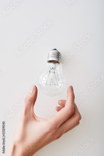 Female hand near the top of an incandescent light bulb upside-down