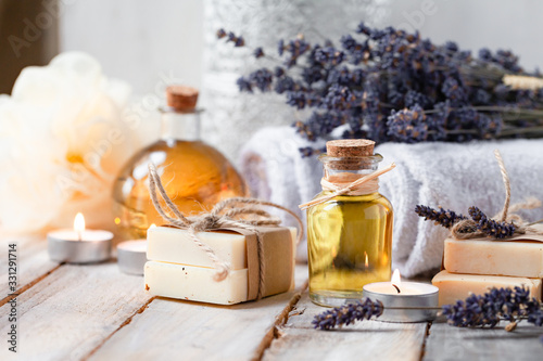 Concept of using natural oil in cosmetology. Moisturizing skin care and aromatherapy. Gentle body treatment. Handmade soap bar, lavender flowers. Atmosphere of harmony and relax. Wooden background photo