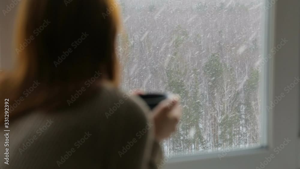 Woman drinking tea near the window