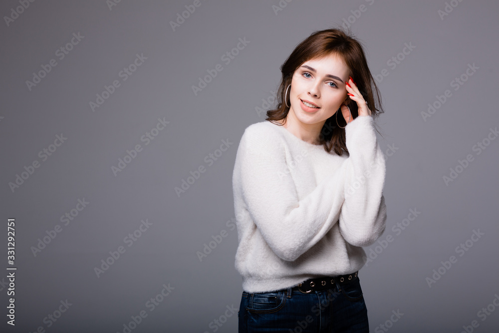 Young Spanish Girl in a light sweater playfully put her hand behind her head and looks at the camera cheerfully Young Spanish Girl in a light sweater playfully put her hand behind her head and looks at the camera cheerfully