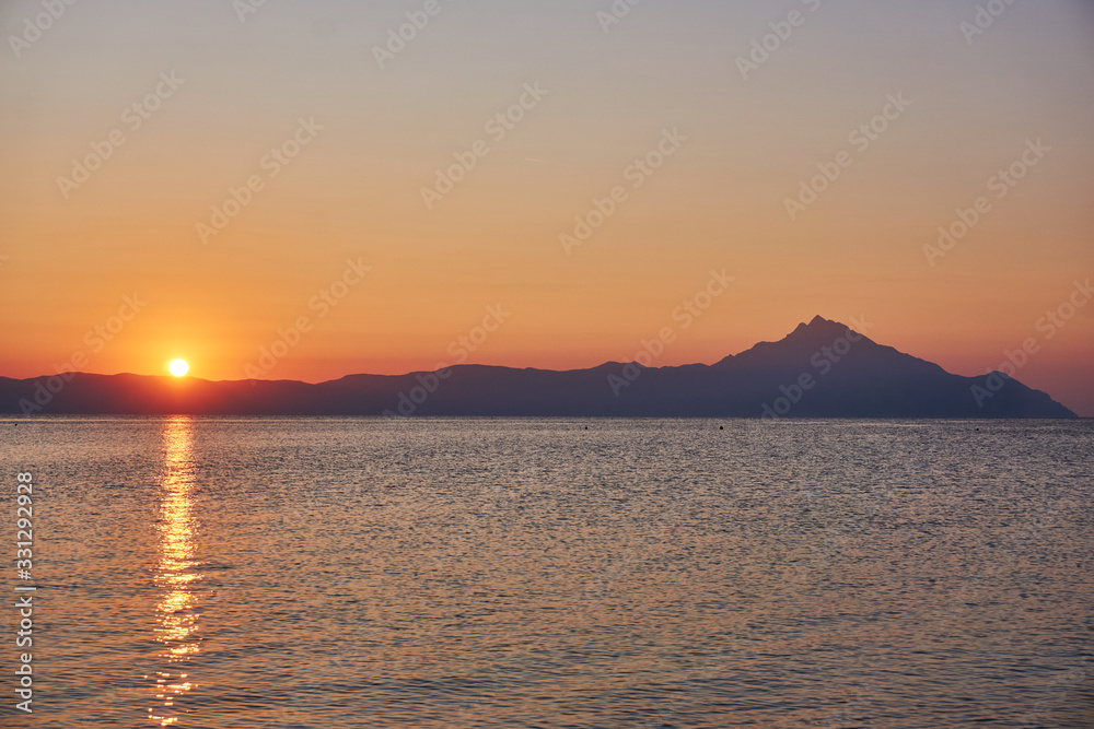 Wonderful sunrise view behind the mountains and next to the sea