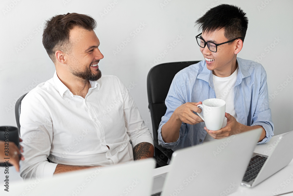 Multiracial colleagues talking during break in office