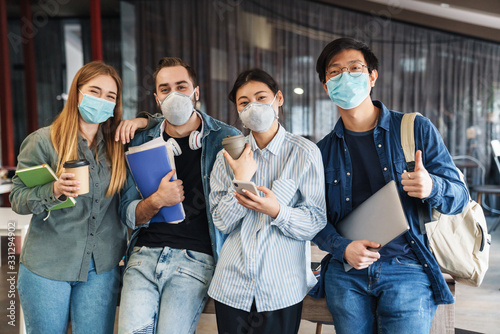 Photo of multinational students in medical masks showing thumb up