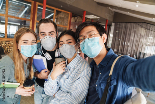 Photo of joyful students in medical masks taking selfie photo