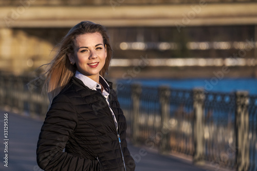 Portrait of Beautiful Smiling Girl Standing On Embankment In The City at Sunny Day.