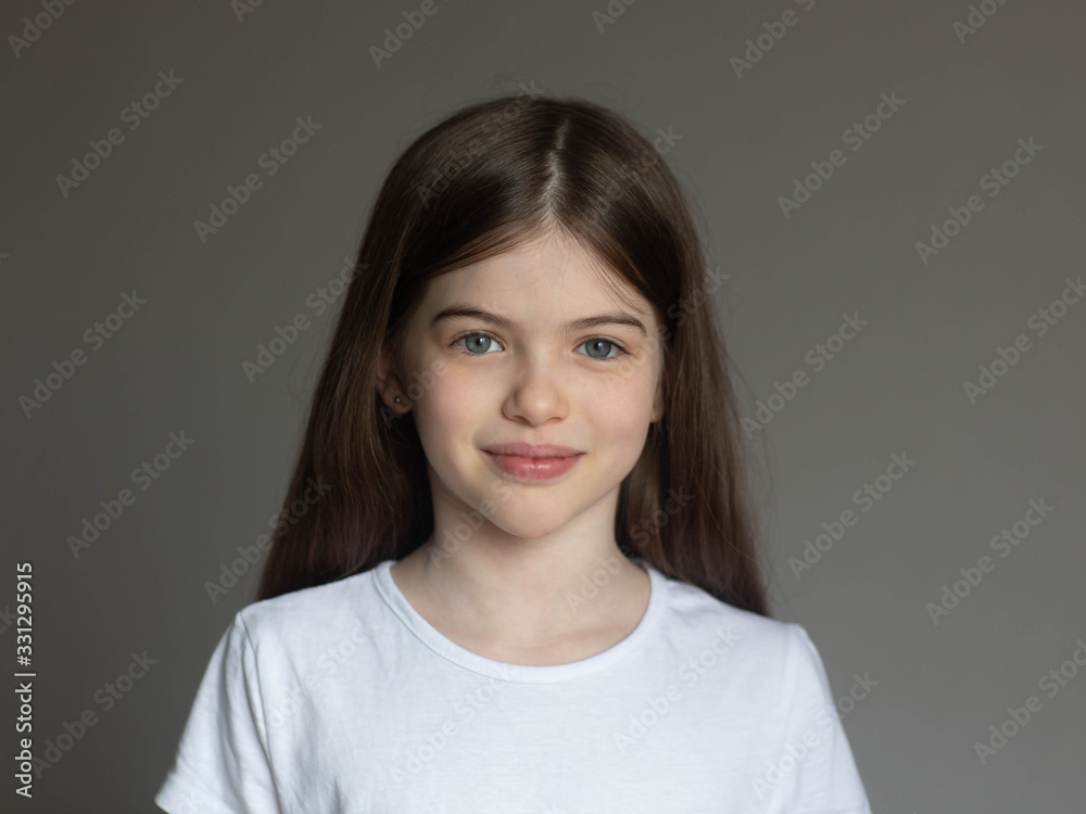 Portrait of a beautiful smiling, little/ young brunette girl in a white T-shirt. Close-up face of european girl. T-shirt design concept Portrait of a beautiful smiling, little/ young brunette girl in a white T-shirt. Close-up face of european girl. T-shirt design concept