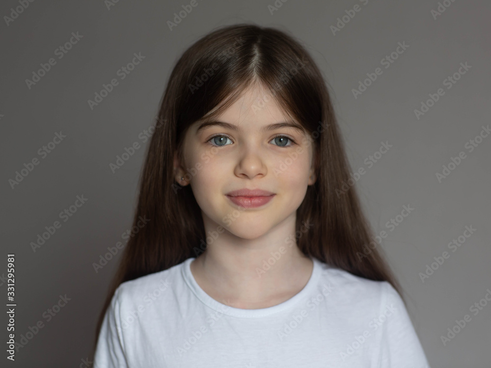 Portrait of a beautiful smiling, little/ young brunette girl in a white T-shirt. Close-up face of european girl. T-shirt design concept Portrait of a beautiful smiling, little/ young brunette girl in a white T-shirt. Close-up face of european girl. T-shirt design concept